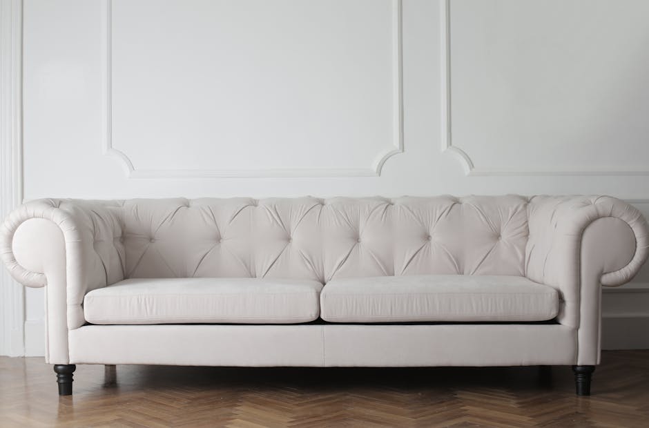 A close-up view of an antique-style upholstered armchair with a wooden frame, featuring floral-patterned fabric on the cushions and woven cane detailing on the backrest, situated on a checkered tile floor with green and beige squares. The room has soft, natural lighting, highlighting the fabric's cleanliness and the wood's polished finish, indicative of professional deep cleaning and surface sanitisation. The background shows a portion of a rustic wall and a white bowl placed nearby, suggesting a period home's interior setting. This image exemplifies domestic cleaning and maintenance of period furniture, aligning with services offered by Carpet Cleaning Holland Park for enhancing hygiene and preserving the appearance of historic home furnishings.
